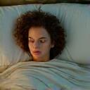 Person sleeping peacefully in a comfortable bed, surrounded by soft, calming light, depicting sleep quality and restful recovery.