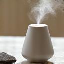 Small essential oil diffuser with gentle mist and a few smooth stones